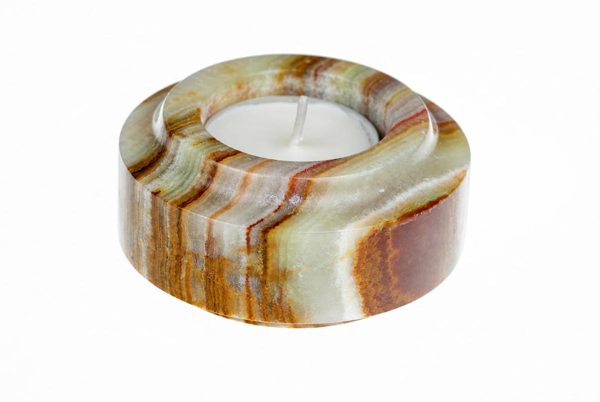 A cylindrical candle holder with a polished, striped pattern of green, brown and white stone, containing an unlit white tea light on a white background.