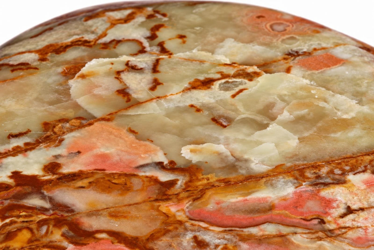 A polished, round stone with swirling patterns of pale cream, pink, and dark brown on a white background.