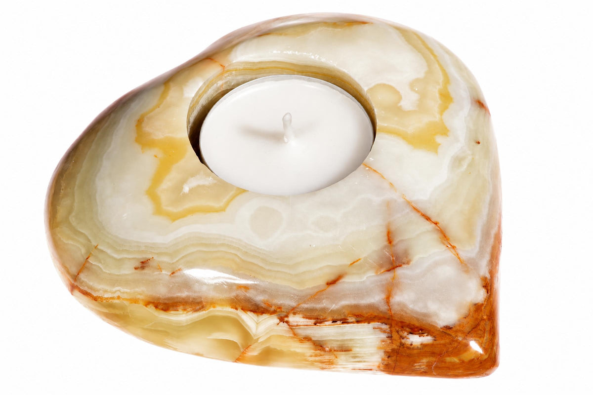 A heart-shaped onyx candle holder with a white tea light, featuring cream, yellow and brown swirls on a white background.