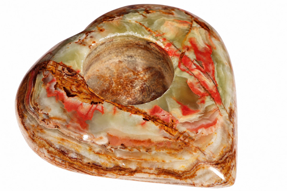 A polished, heart-shaped stone with a central hole. It features swirling layers of pale green, white, red, and brown on a plain background.