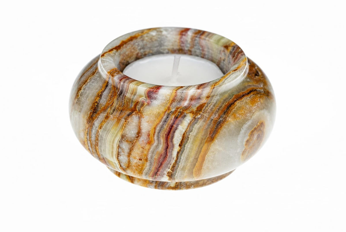 A round candle holder with swirling brown, white and grey stripes holds a white tea light on a pale surface.