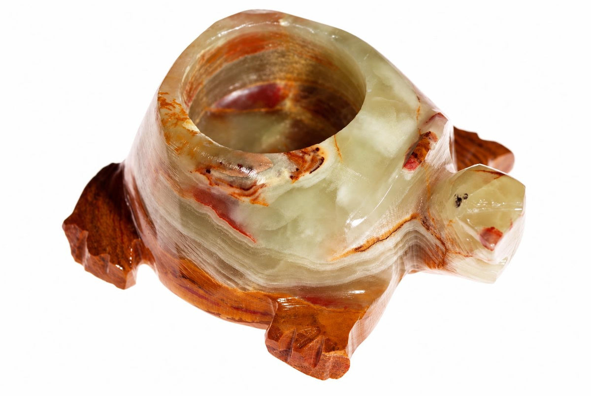 A carved onyx turtle candle holder with a pale green shell and dark brown limbs, set against a white background.