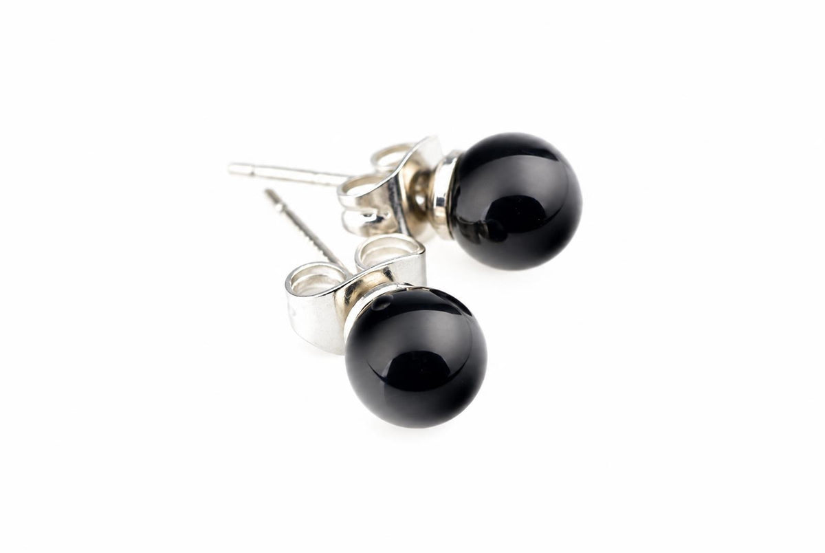 A pair of stud earrings with round black beads and silver-toned posts on a white surface.