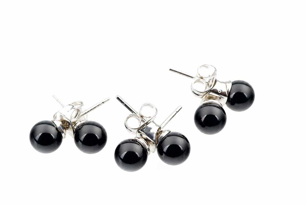 Three pairs of silver-toned stud earrings with round black beads on a white background.