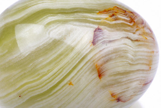A polished, egg-shaped stone with wavy bands of pale green, white, and brown on a plain background.