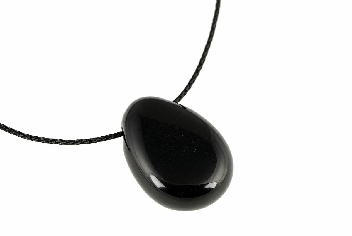 A black, teardrop-shaped pendant with a smooth surface hangs from a dark cord against a white background.
