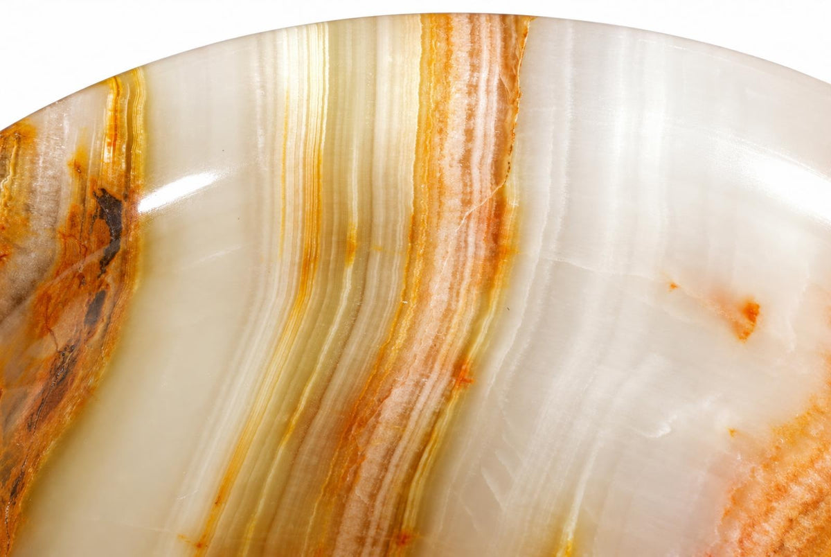 A close-up of a polished stone surface with white, cream, and orange-brown wavy stripes on a dark background.