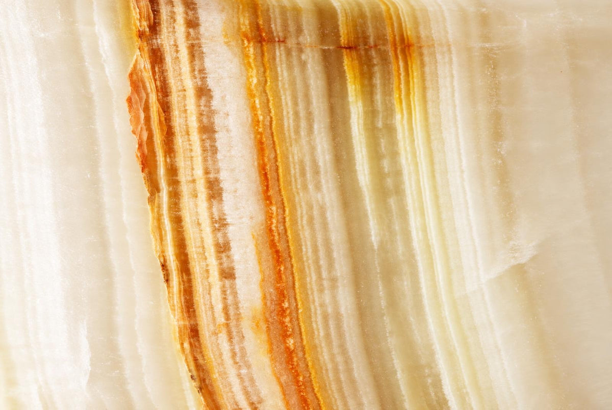 A close-up of a polished stone surface with vertical stripes in cream, pale yellow, and dark brown.