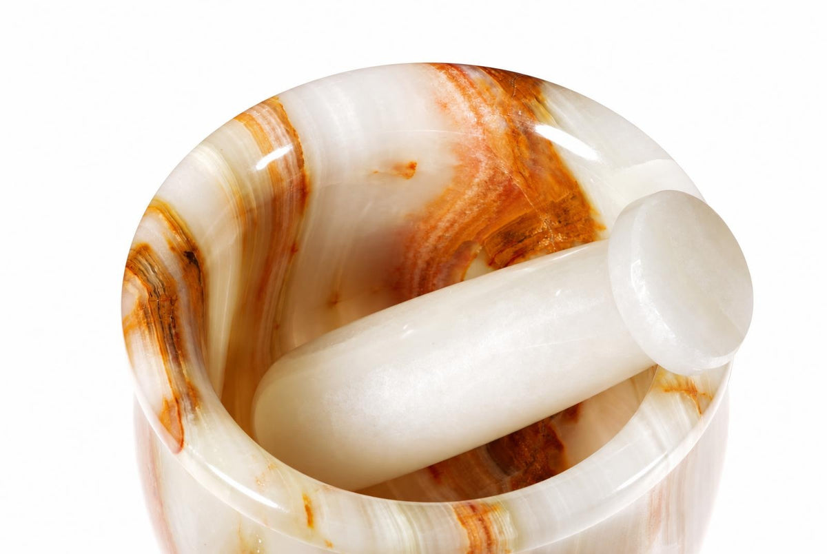 A polished onyx mortar and pestle set with white and brown swirls, shown against a pale surface.