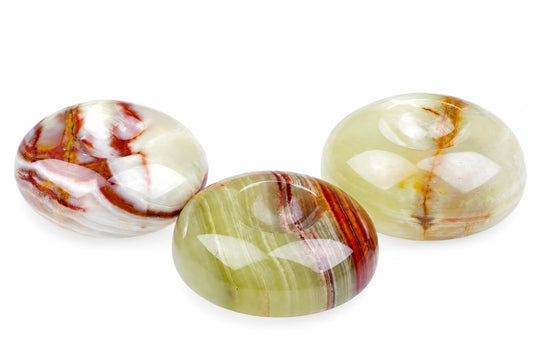 Three polished, oval-shaped stones with swirling red, white, and green patterns rest on a pale surface.