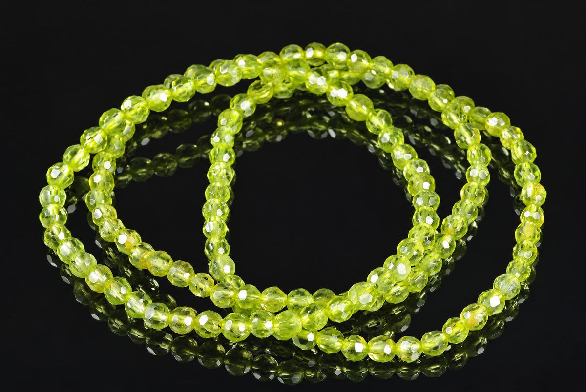 A strand of faceted, lime-green beads arranged in a loose coil on a dark, reflective surface.