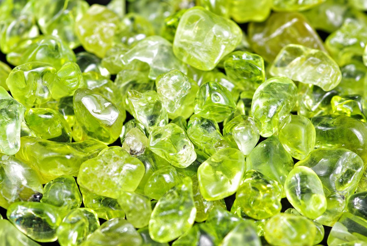 A pile of small, translucent green stones with irregular shapes on a dark surface.