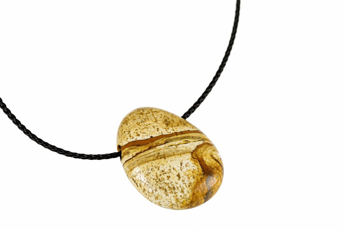 A polished oval pendant with cream, brown and tan banding hangs on a black cord against a white background.