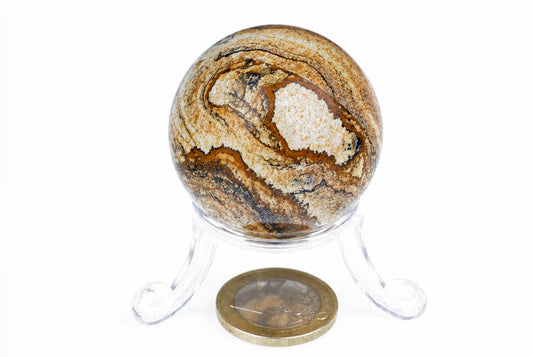 A polished jasper sphere with swirling brown, black and white patterns sits on a clear plastic stand against a white background.