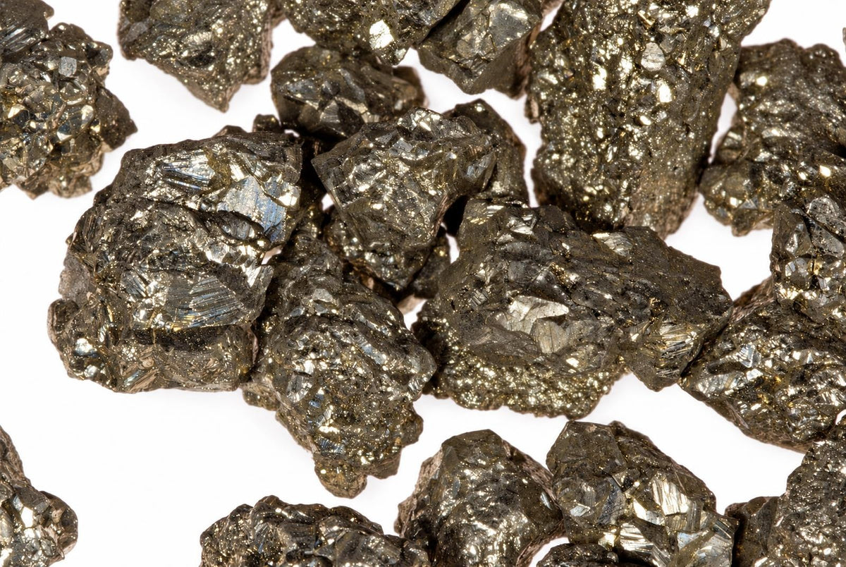 Several metallic, golden-brown mineral chunks with a crystalline texture are scattered on a white surface.