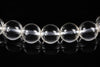 A row of clear, round quartz beads with internal inclusions on a dark reflective surface.