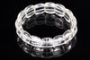 A clear quartz bracelet with smooth, rounded beads arranged in a circle on a dark reflective surface.