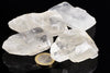 Four clear quartz crystals on a dark surface with a one euro coin for scale.