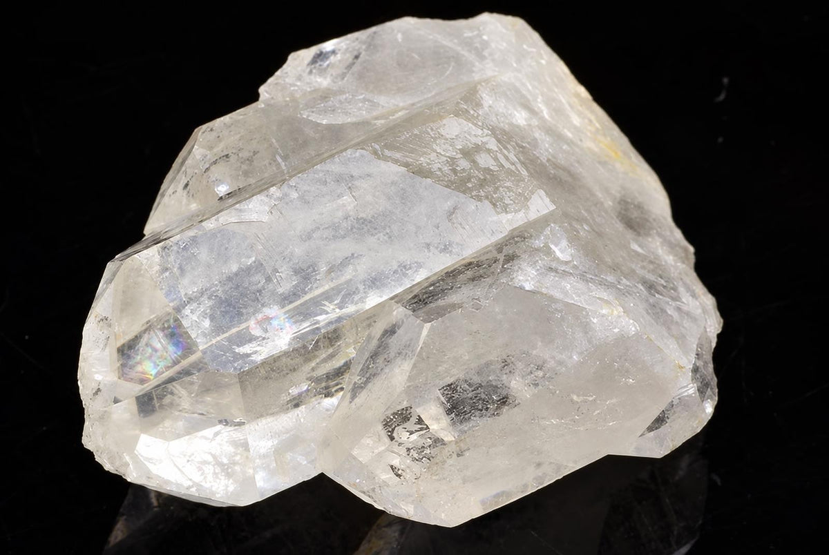 A large, clear quartz crystal with a rough, angular shape and visible internal fractures on a dark surface.