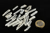Several clear quartz points on a dark surface, with a one-euro coin for scale.