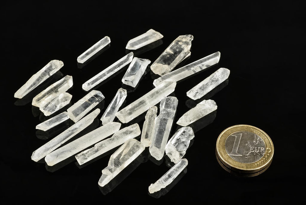 Several clear quartz points on a dark surface, with a one-euro coin for scale.
