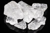 Several clear, translucent quartz crystals with rough shapes rest on a dark surface.