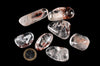 Polished clear stones with cloudy white areas and reddish-brown inclusions lie beside a one-euro coin on a black background.