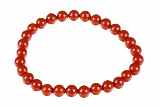 A bracelet made of round, red beads arranged in a circle on a white background.