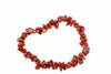 A bracelet made of irregular red jasper chips arranged in a circle on a white surface.