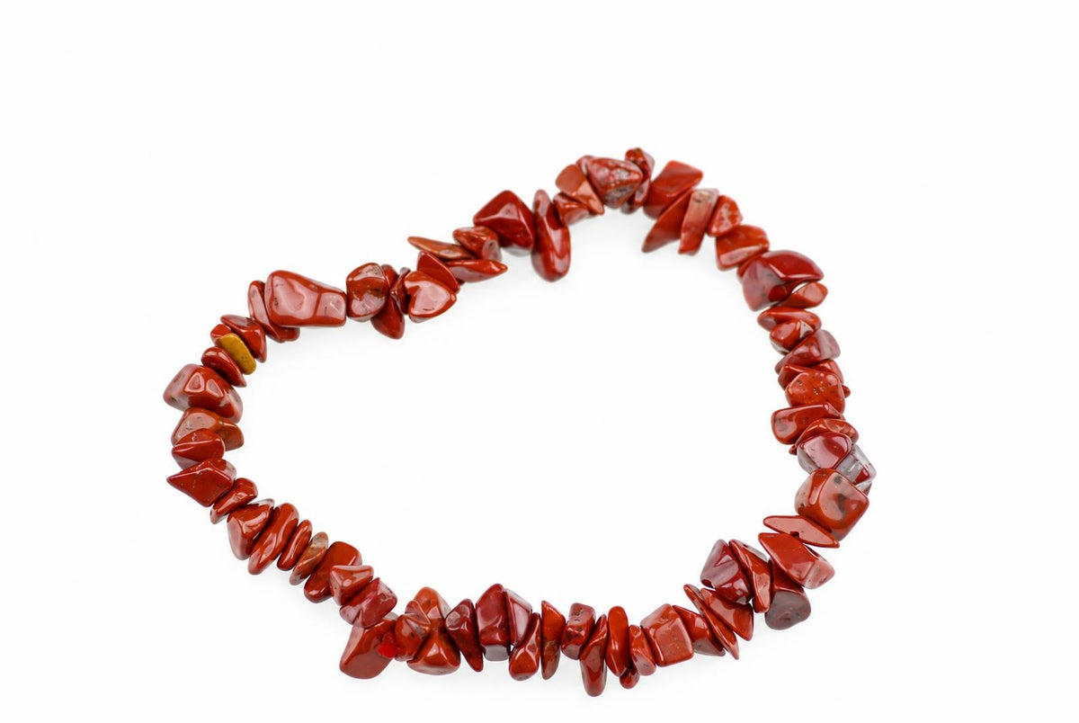 A bracelet made of irregular red jasper chips arranged in a circle on a white surface.