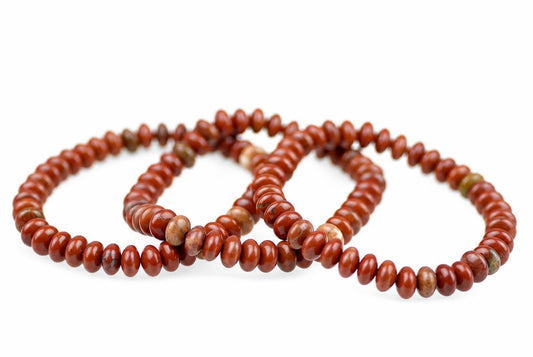 A bracelet made of round, reddish-brown beads with some lighter and green-toned accents on a white background.
