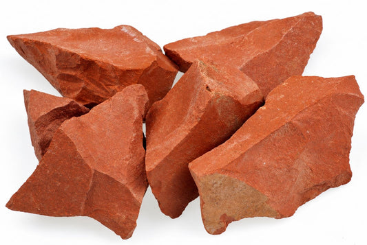 A pile of five rough, angular red jasper stones on a white surface.