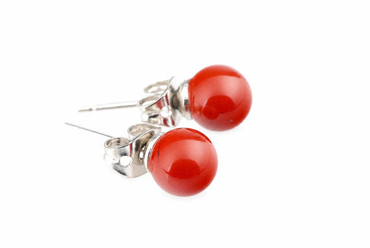 A pair of stud earrings with round red jasper beads and silver-toned posts on a white surface.