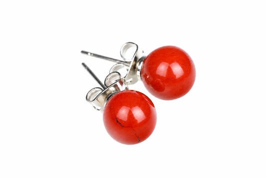 A pair of round red jasper stud earrings with silver-toned posts and butterfly backs on a white surface.