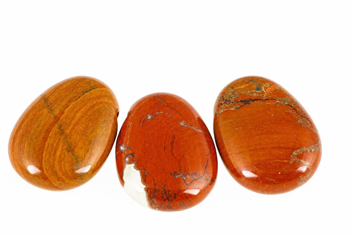Three polished, oval-shaped stones in shades of orange and brown with natural patterns on a white background.