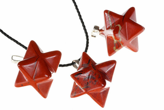 Three red jasper pendants have intersecting pointed star shapes and pale natural markings, arranged with a black cord on white.