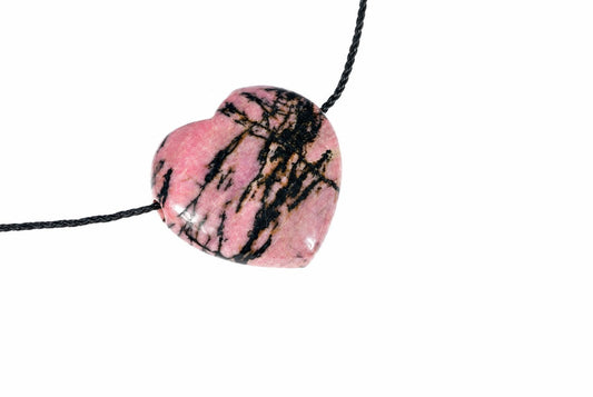 A heart-shaped pink stone pendant with black veins on a dark cord, set against a white background.
