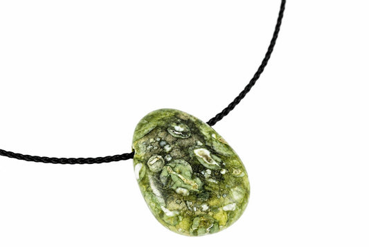 A polished green rhyolite pendant with white and dark inclusions hangs on a black cord against a white background.