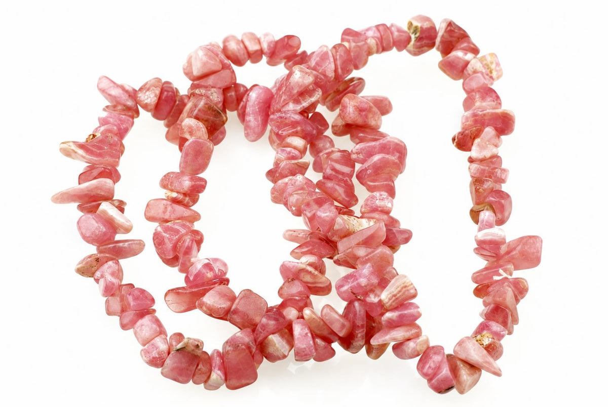A bracelet made of irregular pink rodochrosite chips arranged in a loose coil on a white surface.