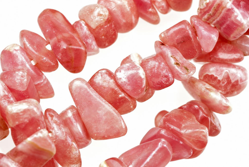 A strand of pink rodochrosite chips strung together on a white background.