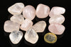 A collection of polished rose quartz stones in pale pink and clear tones, arranged on a dark surface with a one-euro coin for scale.