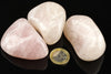 Three polished rose quartz stones on a dark surface with a one euro coin for scale.
