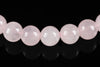 A row of round, pale pink beads on a dark surface with reflections.