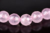A row of faceted, translucent pink beads on a dark surface.