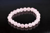 A bracelet of faceted light pink beads on a dark surface.