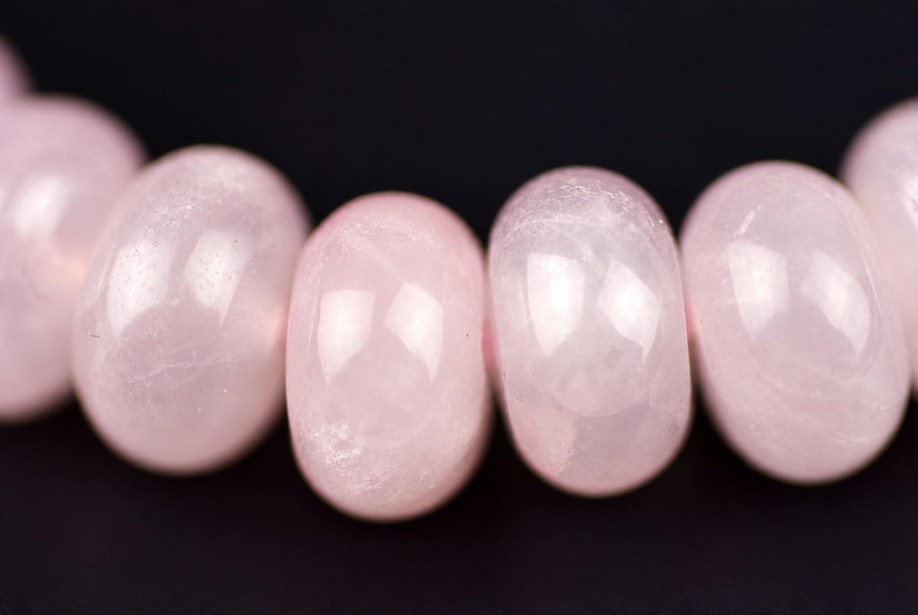 A row of smooth, oval pink beads on a dark surface.