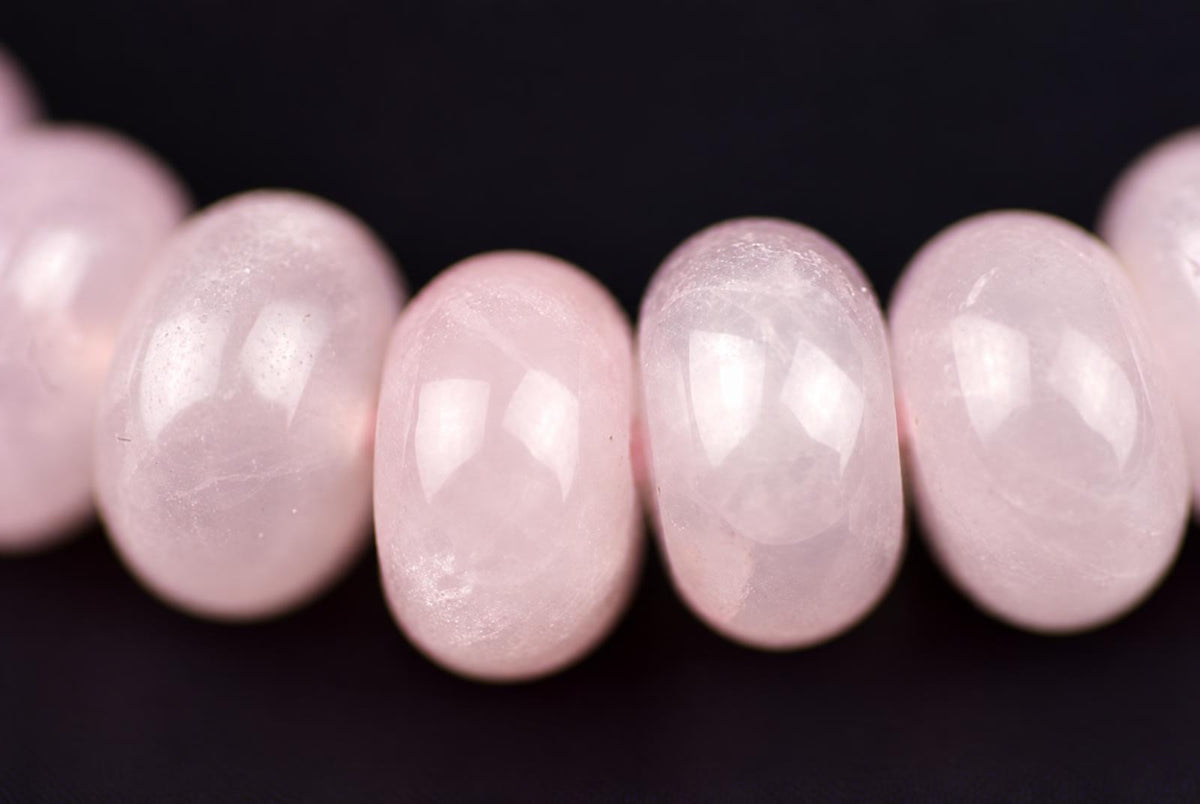 A row of smooth, oval pink beads on a dark surface.