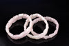 Three rose quartz bracelets with triangular beads lie on a dark surface.