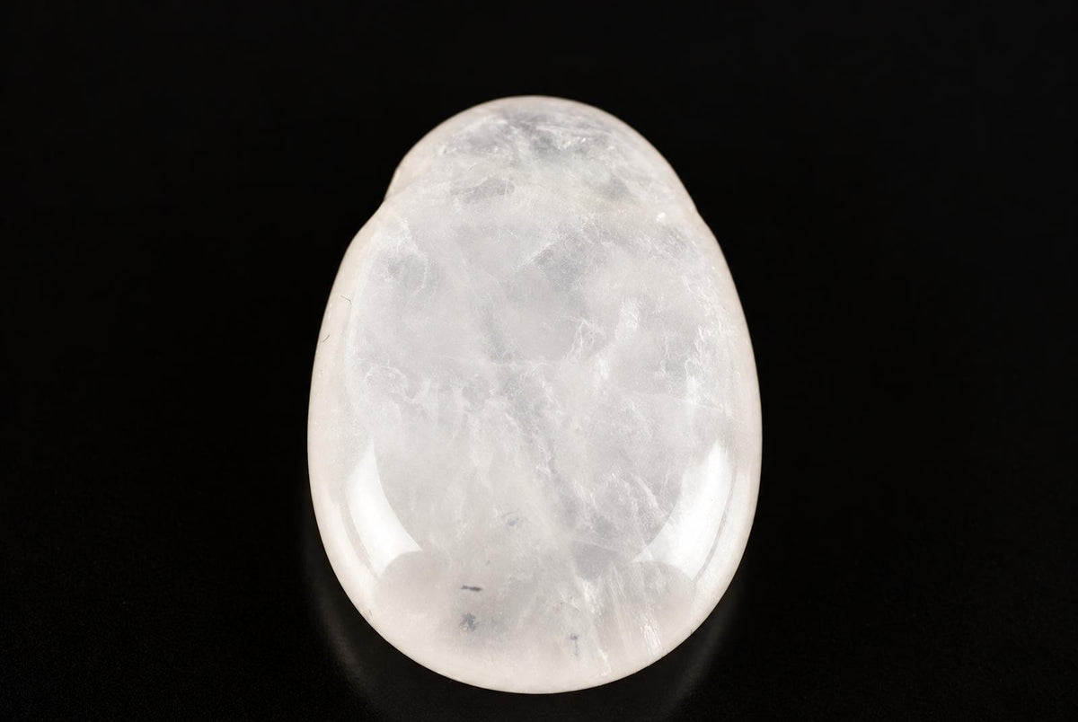 A polished, oval-shaped rose quartz pendant with a smooth white surface and subtle internal patterns, set against a dark background.