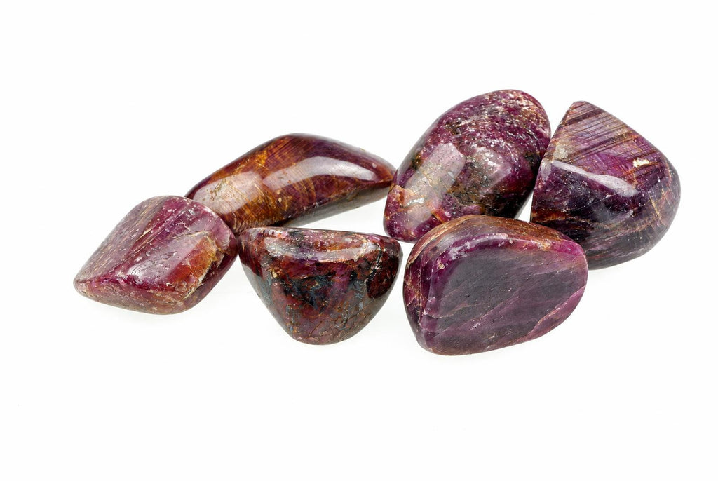 Six polished stones with deep purple and brown hues, arranged on a white surface.